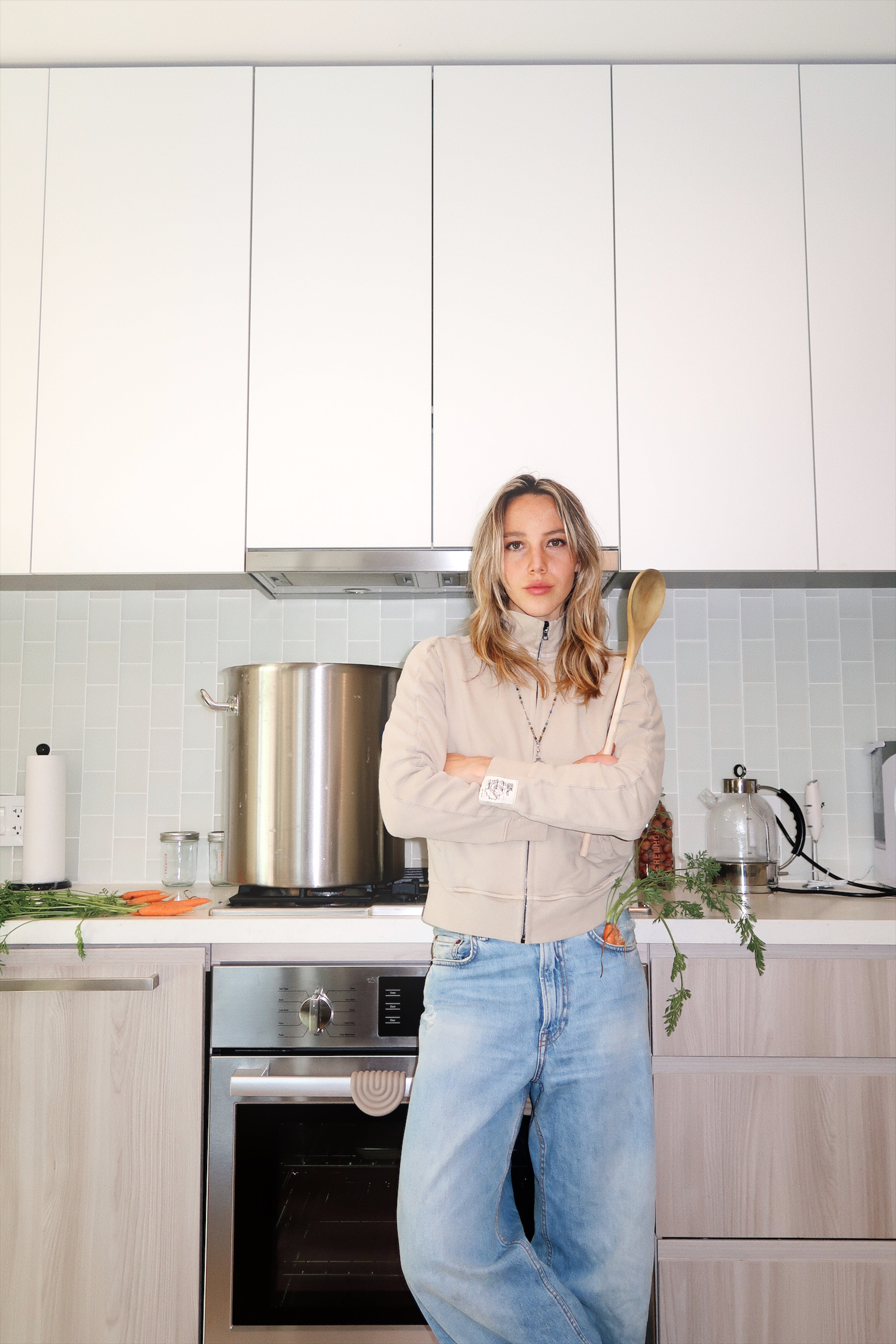 Making natural carrot dye in a home kitchen, using fresh carrot tops to create a soft, plant-based color for organic clothing.