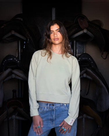 Woman lounging in organic, naturally dyed crewneck made with breathable, toxin-free cotton for ultimate comfort.